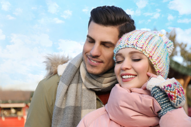 Happy couple in warm clothes at winter fair. Christmas season