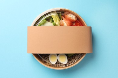 Photo of Tasty food in container on light blue background, top view. Space for text