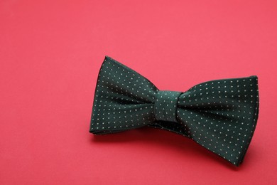 Photo of Stylish black bow tie with polka dot pattern on red background, space for text