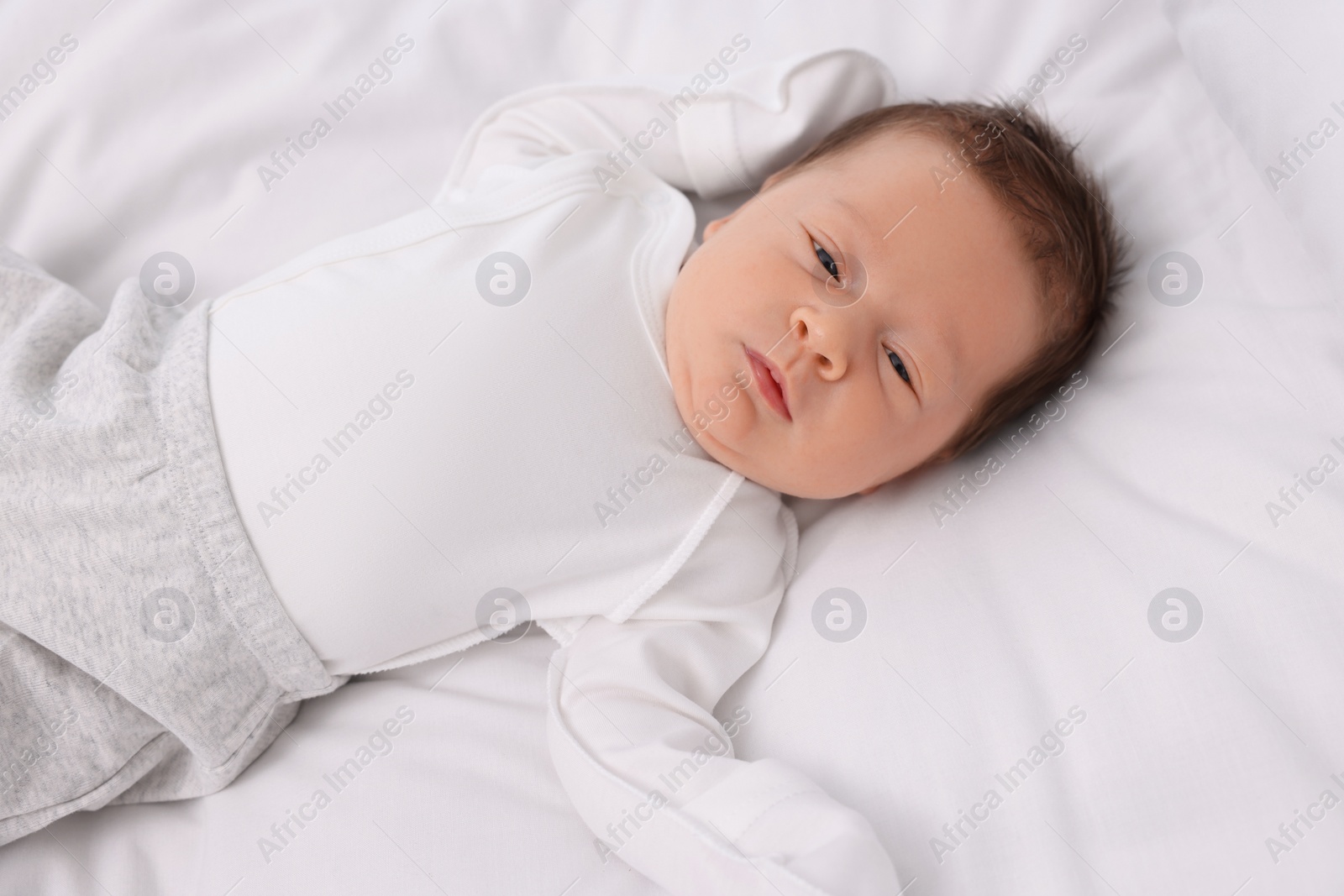 Photo of Cute newborn baby lying on white soft bed