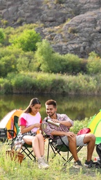 Young couple with hot drinks  resting outdoors. Camping vacation