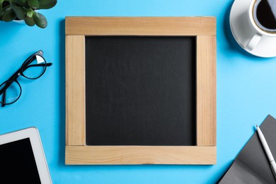 Photo of Flat lay composition with small chalkboard on light blue background, space for text