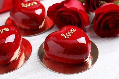 St. Valentine's Day. Delicious heart shaped cakes and roses on white wooden table, closeup