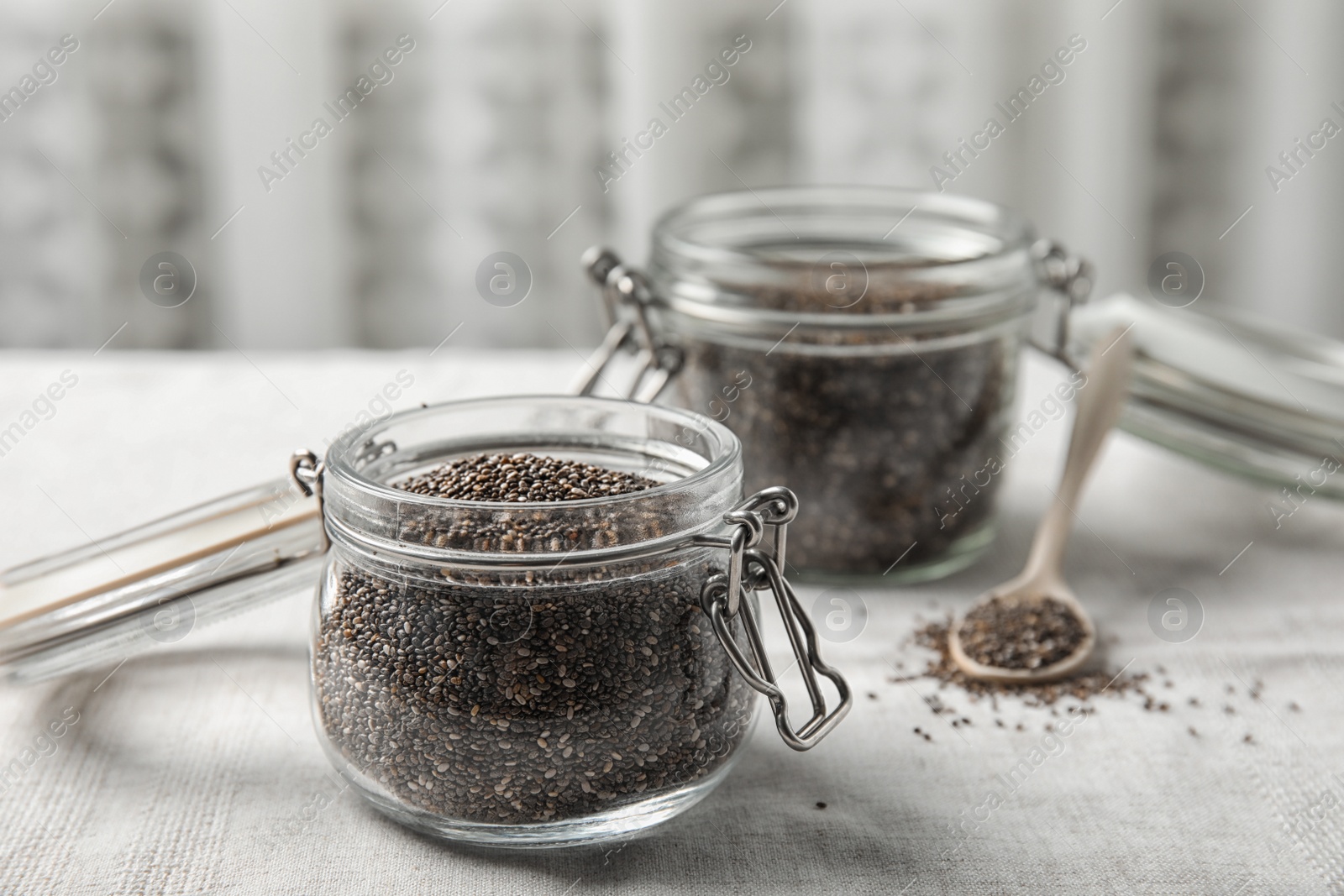 Photo of Glass jars with chia seeds on table against blurred background