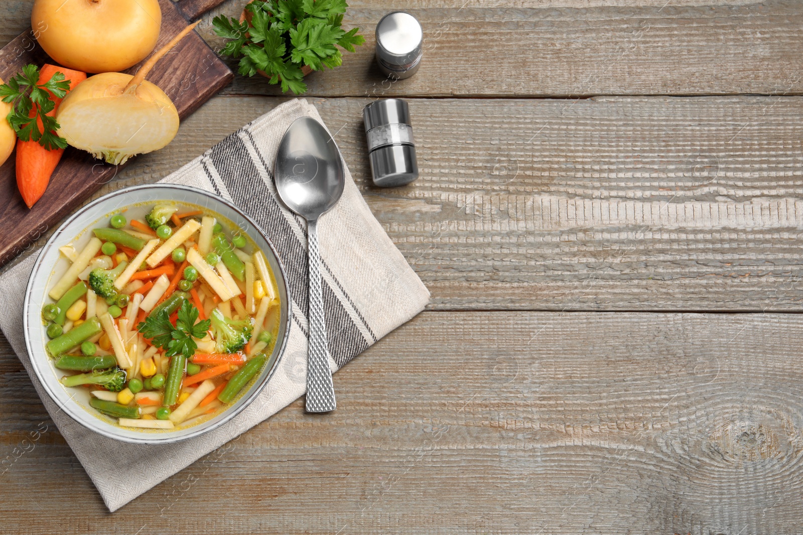 Photo of Bowl of delicious turnip soup served on wooden table, flat lay. Space for text