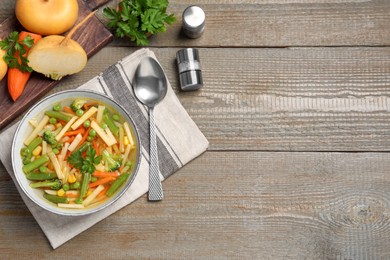 Photo of Bowl of delicious turnip soup served on wooden table, flat lay. Space for text