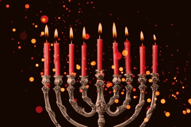 Silver menorah with burning candles on black background, closeup. Hanukkah celebration