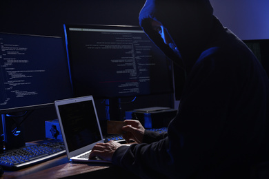 Photo of Hacker with computers and credit card in dark room. Cyber crime