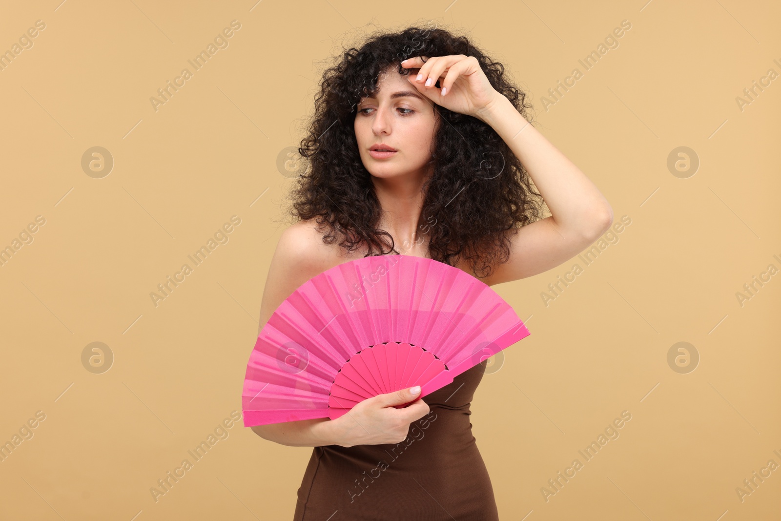 Photo of Woman with hand fan suffering from heat on beige background