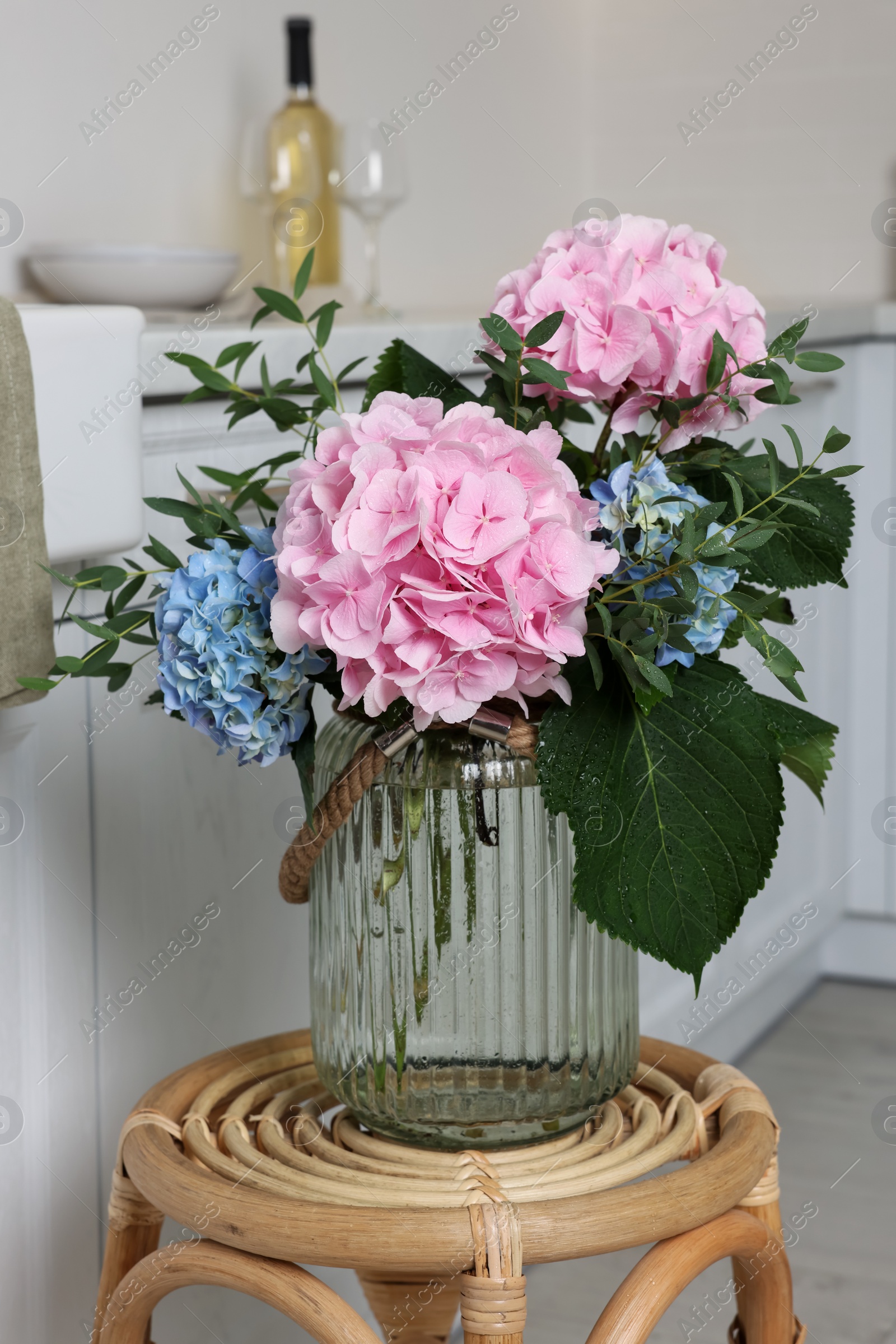 Photo of Beautiful hortensia flowers in vase on stand indoors