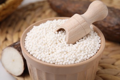 Tapioca pearls and scoop in bowl on wicker mat, closeup