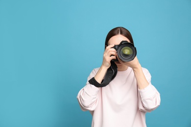Photo of Professional photographer taking picture on light blue background. Space for text