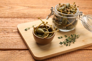 Photo of Delicious pickled capers and thyme twigs on wooden table