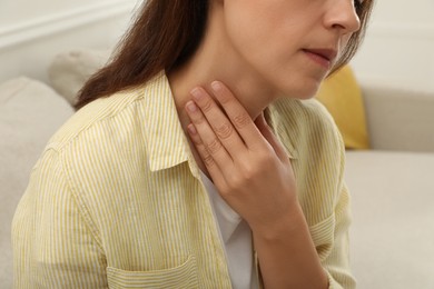 Photo of Mature woman doing thyroid self examination indoors, closeup