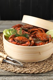 Photo of Delicious boiled crabs with lime and dill served on wooden table