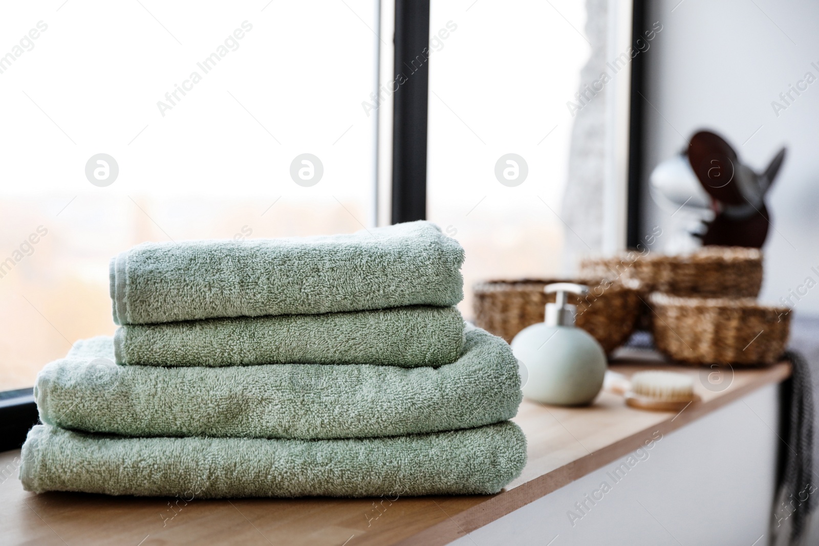 Photo of Stack of clean soft towels on windowsill in bathroom