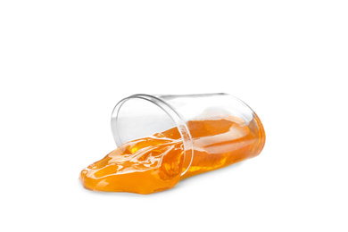 Photo of Overturned plastic container with orange slime isolated on white. Antistress toy