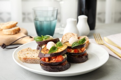 Baked eggplant with tomatoes, cheese and basil served on table