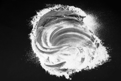 Photo of Scattered flour on black table, top view