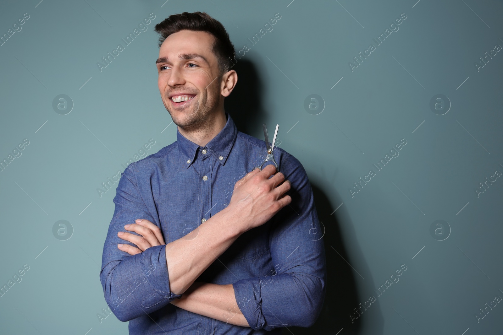 Photo of Professional hairdresser with scissors on color background