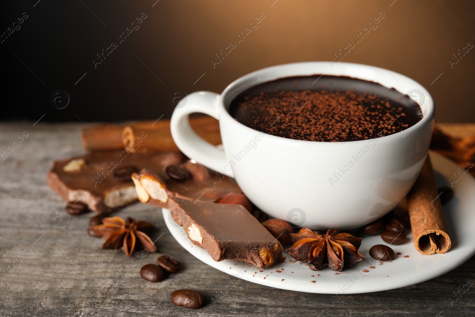 Photo of Cup of delicious hot chocolate, spices and coffee beans on wooden table. Space for text