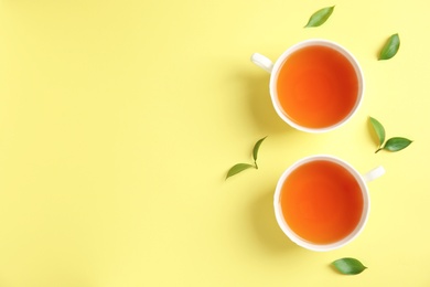 Flat lay composition with delicious tea and green leaves on color background