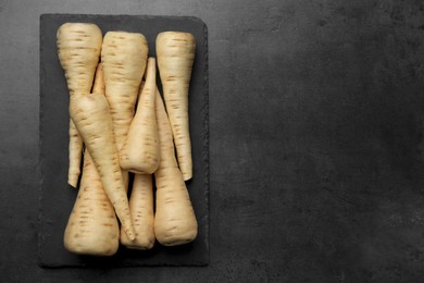 Delicious fresh ripe parsnips on black table, top view. Space for text