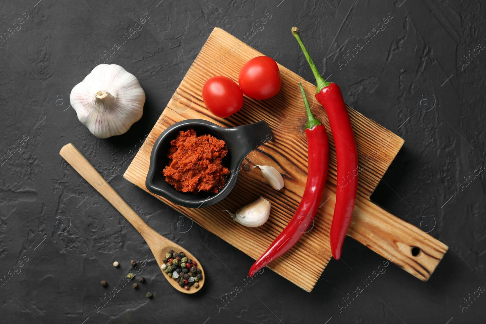 Photo of Dish with red curry paste and ingredients on black table, flat lay