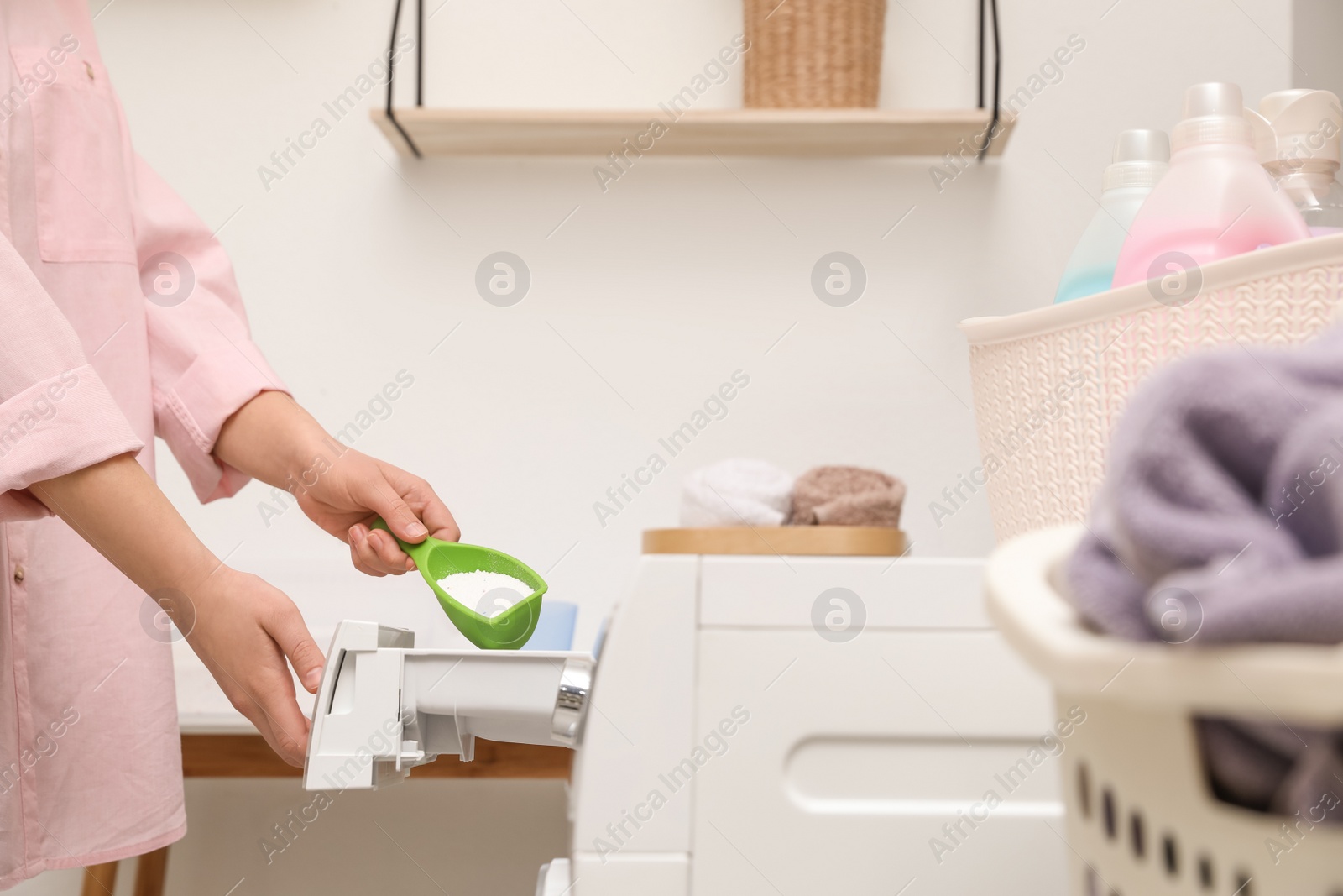 Photo of Woman pouring powder into drawer of washing machine in laundry room, closeup