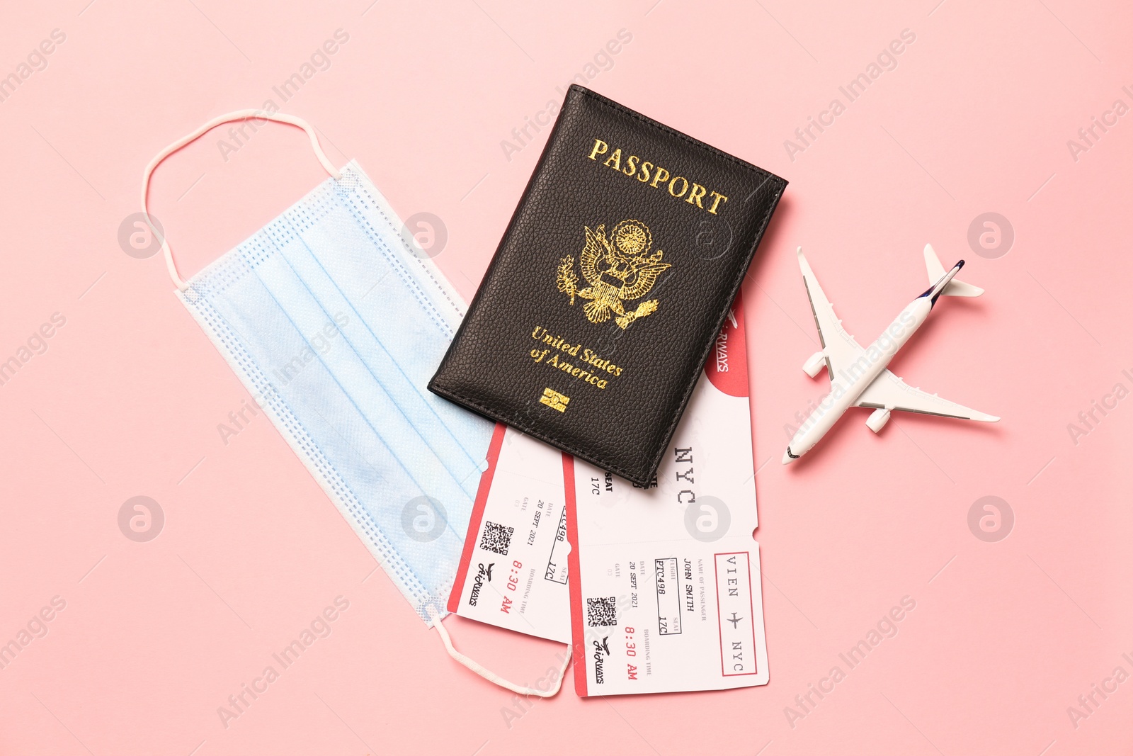 Photo of Flat lay composition with passport and protective mask on pink background. Travel during quarantine