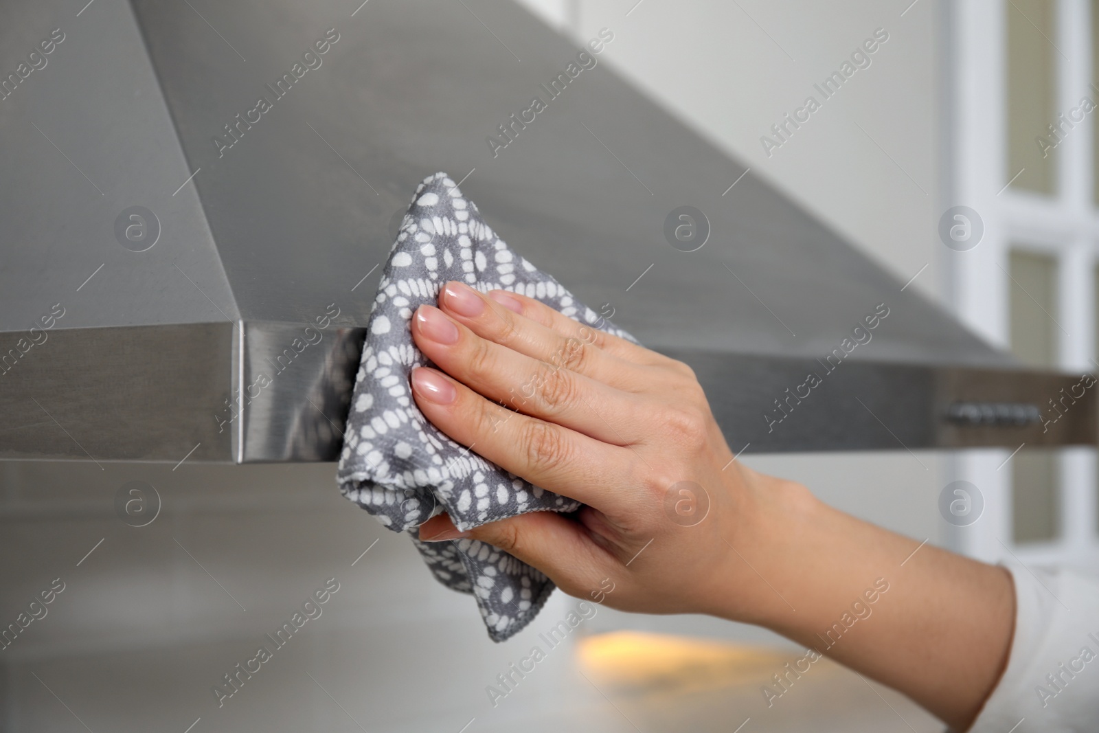 Photo of Woman wiping exhaust hood in kitchen, closeup