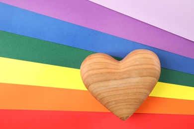 Wooden heart on rainbow background, top view. Gay symbol