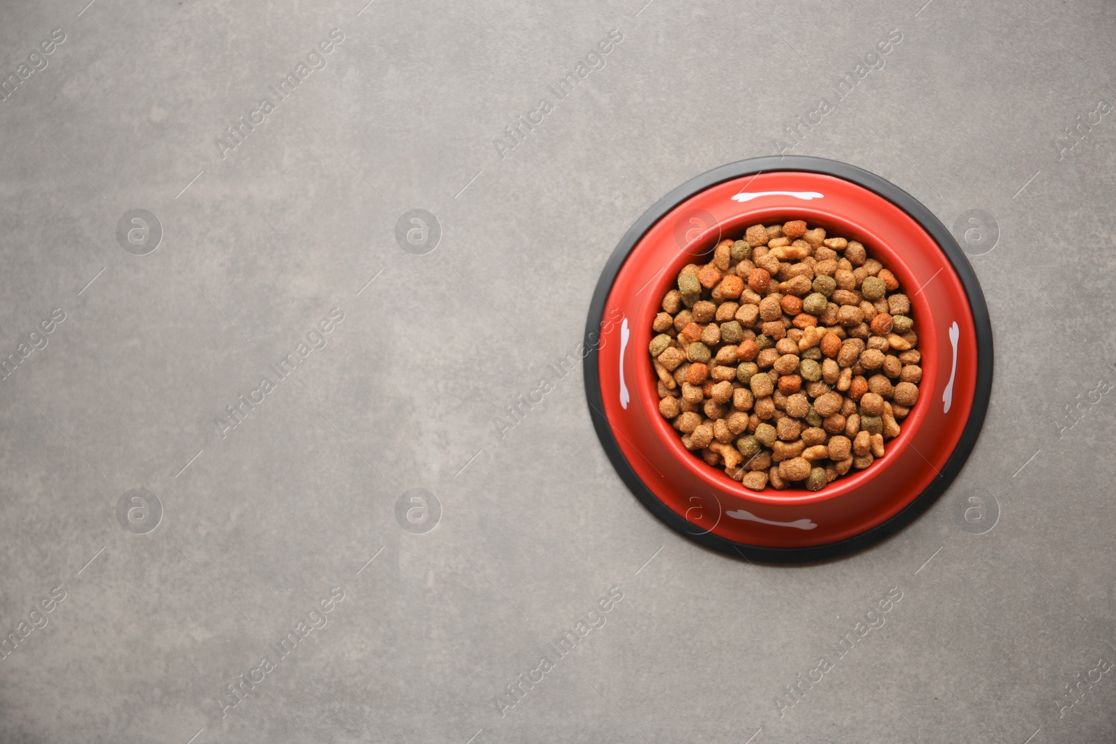 Photo of Dry dog food in feeding bowl on beige floor, top view. Space for text