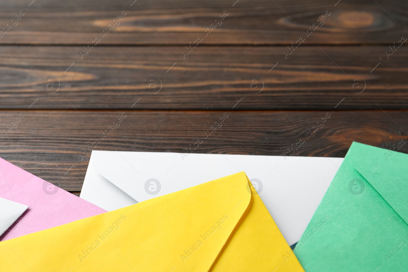 Photo of Colorful paper envelopes on wooden background, closeup. Space for text