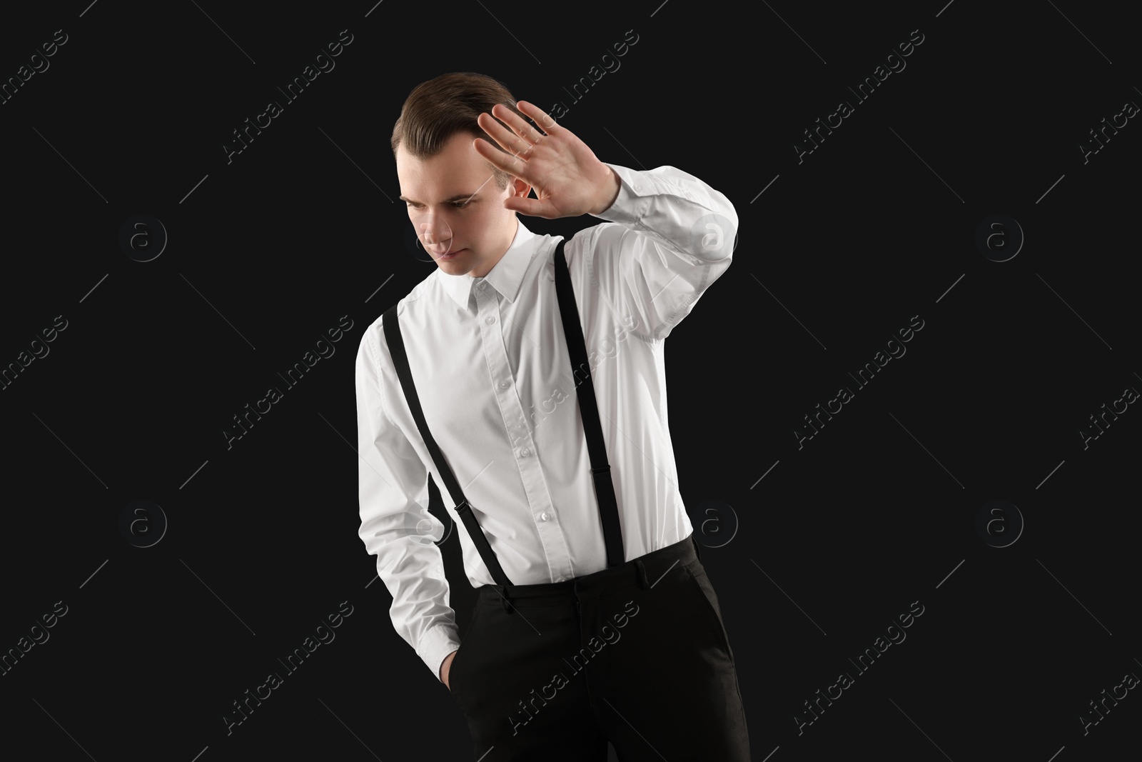Photo of Young man covering face with hand on black background