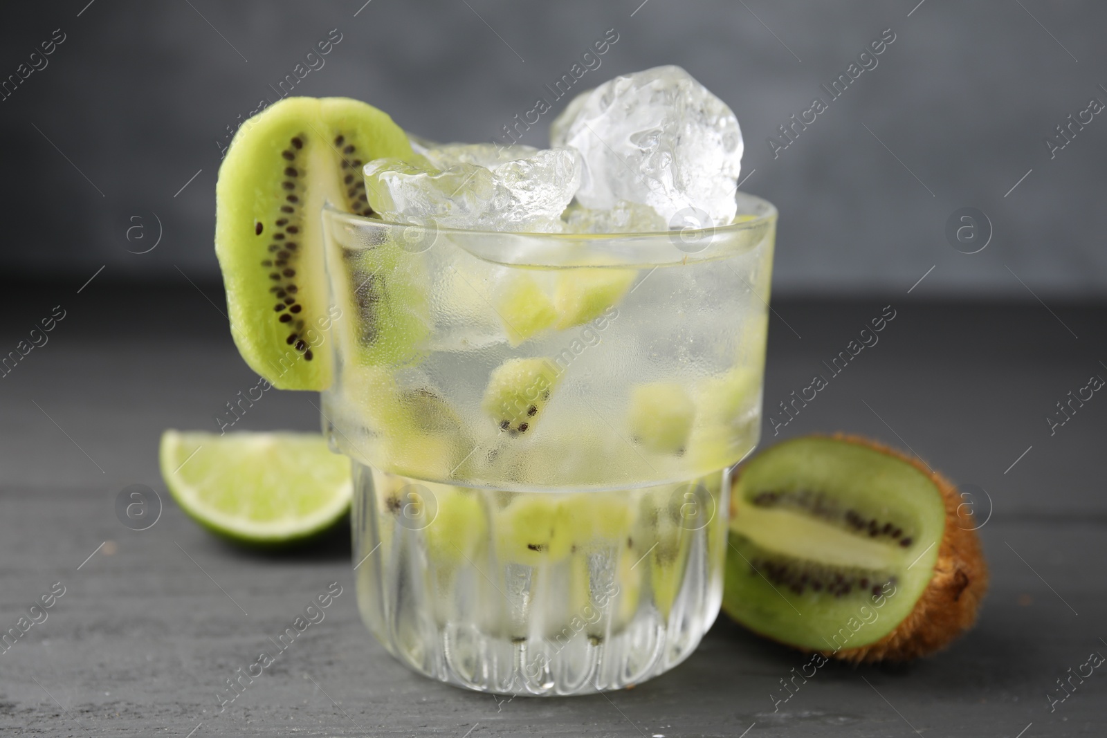 Photo of Glass of refreshing drink and cut kiwi on gray table, closeup