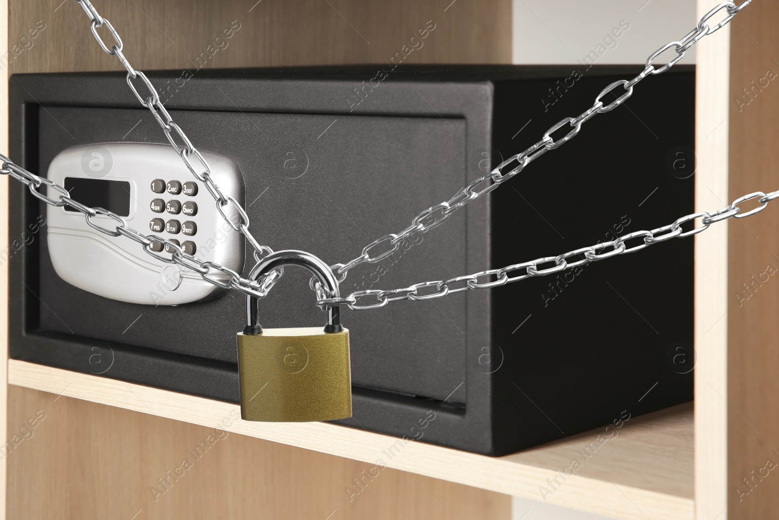 Image of Padlock, chains and black steel safe in wooden closet 