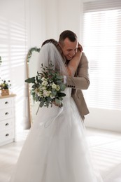 Photo of Happy groom and bride hugging indoors. Wedding day