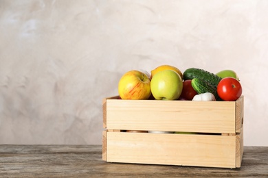 Photo of Wooden crate with fruits and vegetables on table, space for text