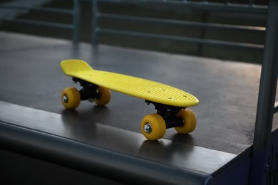 Modern yellow skateboard on top of ramp outdoors in evening