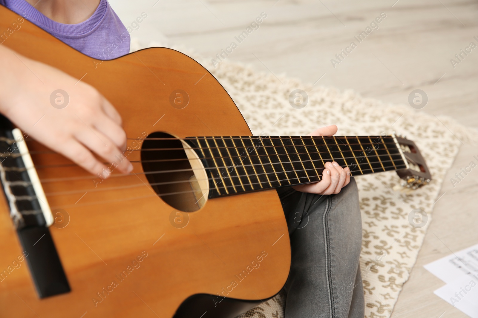 Photo of Little girl playing guitar on floor, closeup
