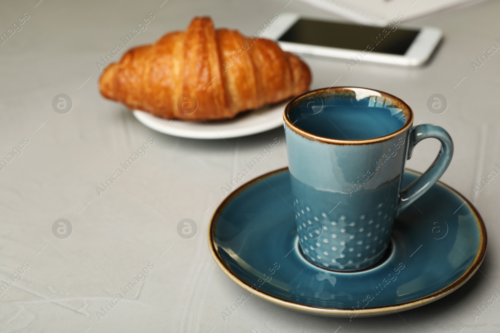 Photo of Empty coffee cup and croissant on grey background. Space for text