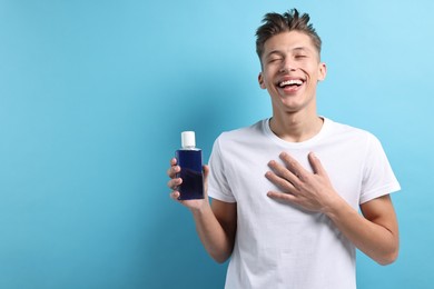 Photo of Young man with mouthwash on light blue background, space for text