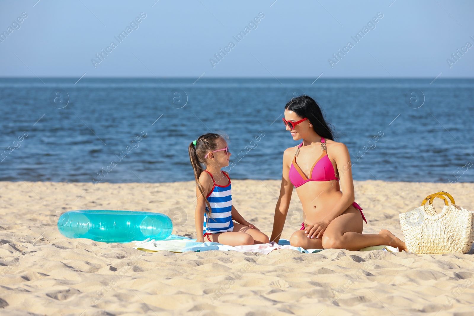 Photo of Happy mother and daughter on sandy beach near sea. Summer holidays with family