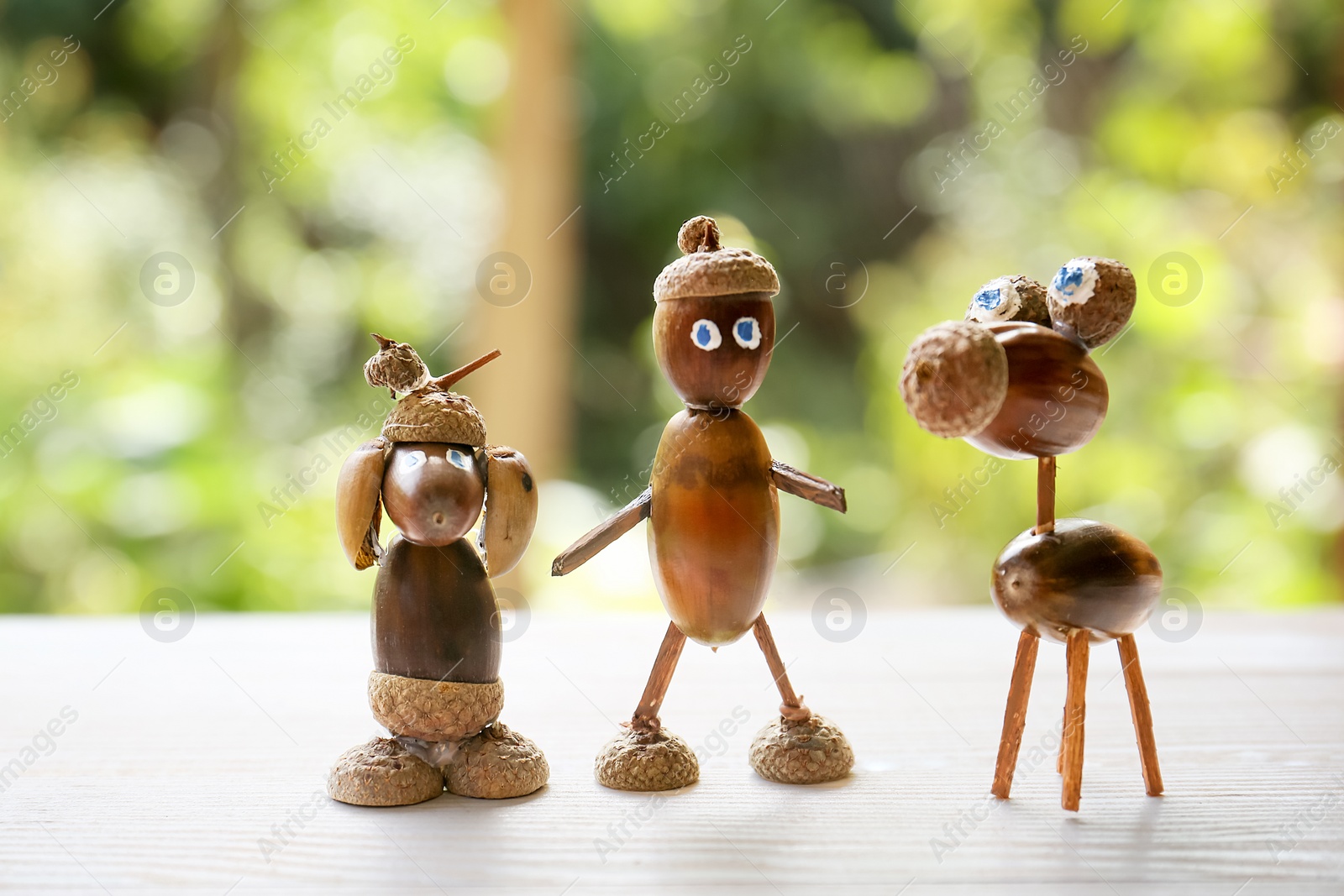 Photo of Cute figures made of acorns on white wooden table