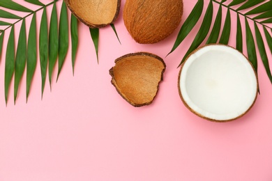 Photo of Fresh coconuts and palm leaves on pink background, flat lay