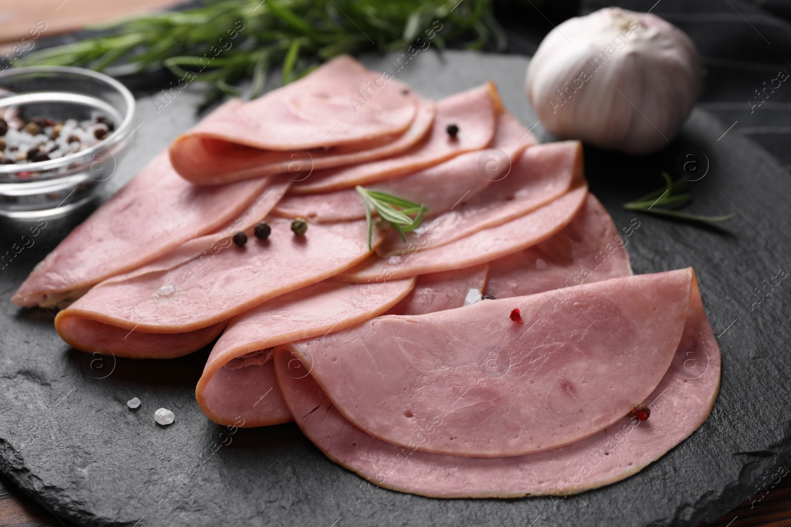 Photo of Tasty ham with rosemary, garlic and peppercorns on table, closeup