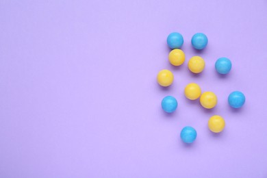 Photo of Many bright chewy gumballs on lilac background, flat lay. Space for text
