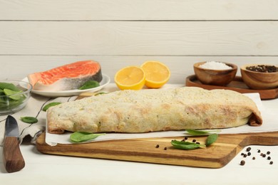 Photo of Delicious strudel with tasty filling and basil served on white wooden table