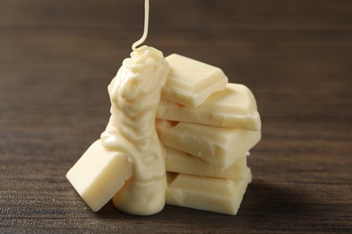 Pouring tasty white chocolate paste onto pieces on wooden table, closeup